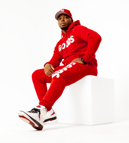 A red hooded sweatsuit made of cotton and polyester, featuring black logo embroidery on the chest and leg.